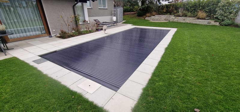 Pool mit geschlossener Rollladen-Abdeckung in einem Garten – ein Badipool-Projekt