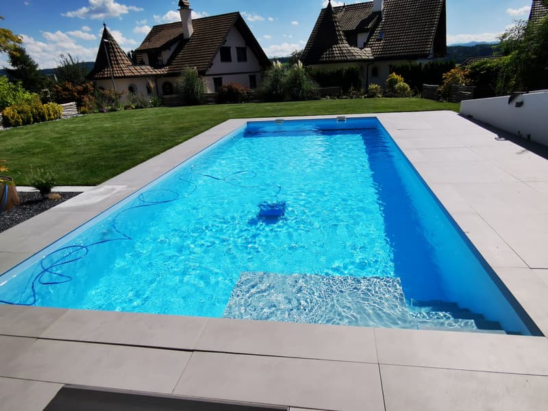 Rechteckiger Pool mit Rasen und heller Terrasse