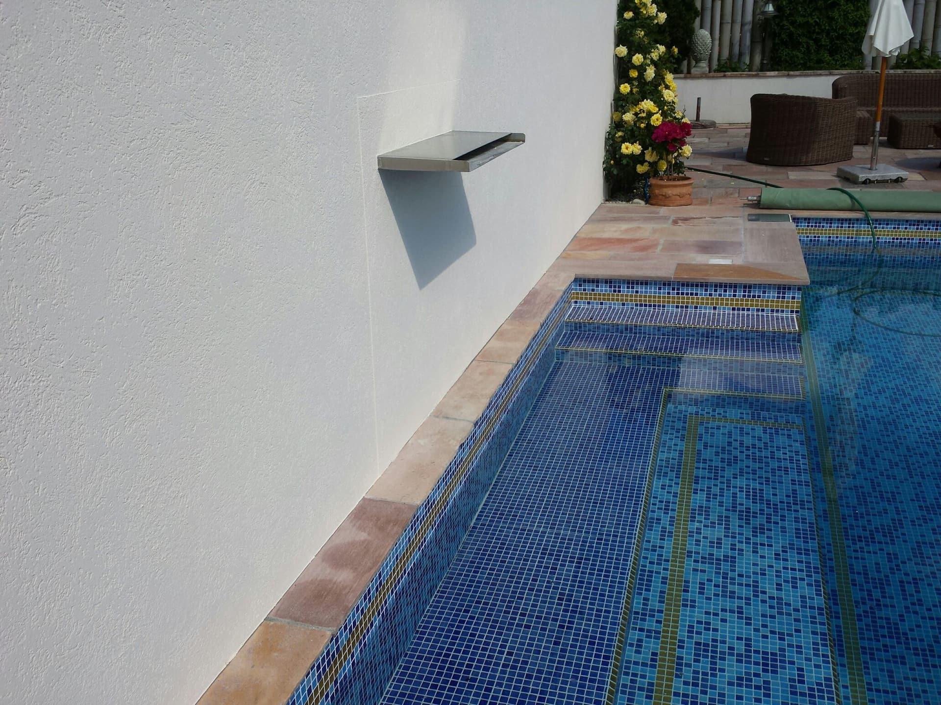 Pool mit Mosaik und Schwallwasser bei Sommerlicht